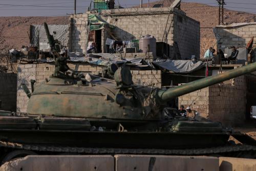 People sit on their terrace near an abandoned tank that belongs to the ousted Syrian President Bashar al-Assad's forces, on the outskirts of Damascus, Syria January 2, 2025.
